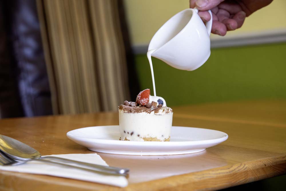 Cream poured over an individual berry-topped dessert
